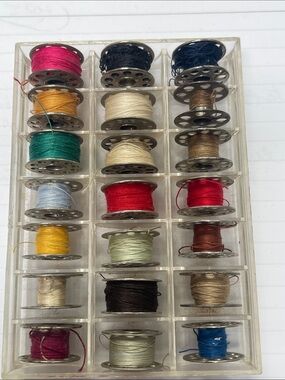 21 vintage metal bobbins in plastic tray